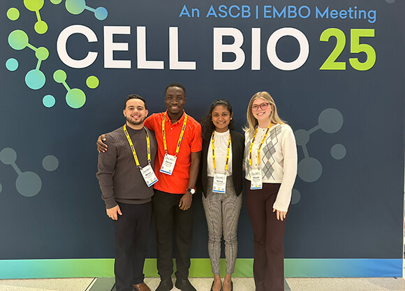 Students and professor standing in front of the CellBio Conference Poster