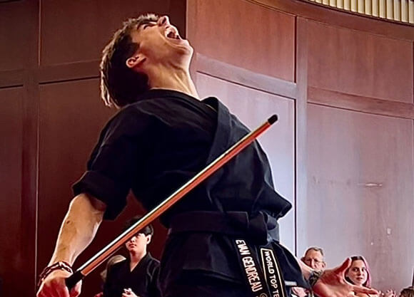 Evan Gendreau holding a wooden dowel and yelling