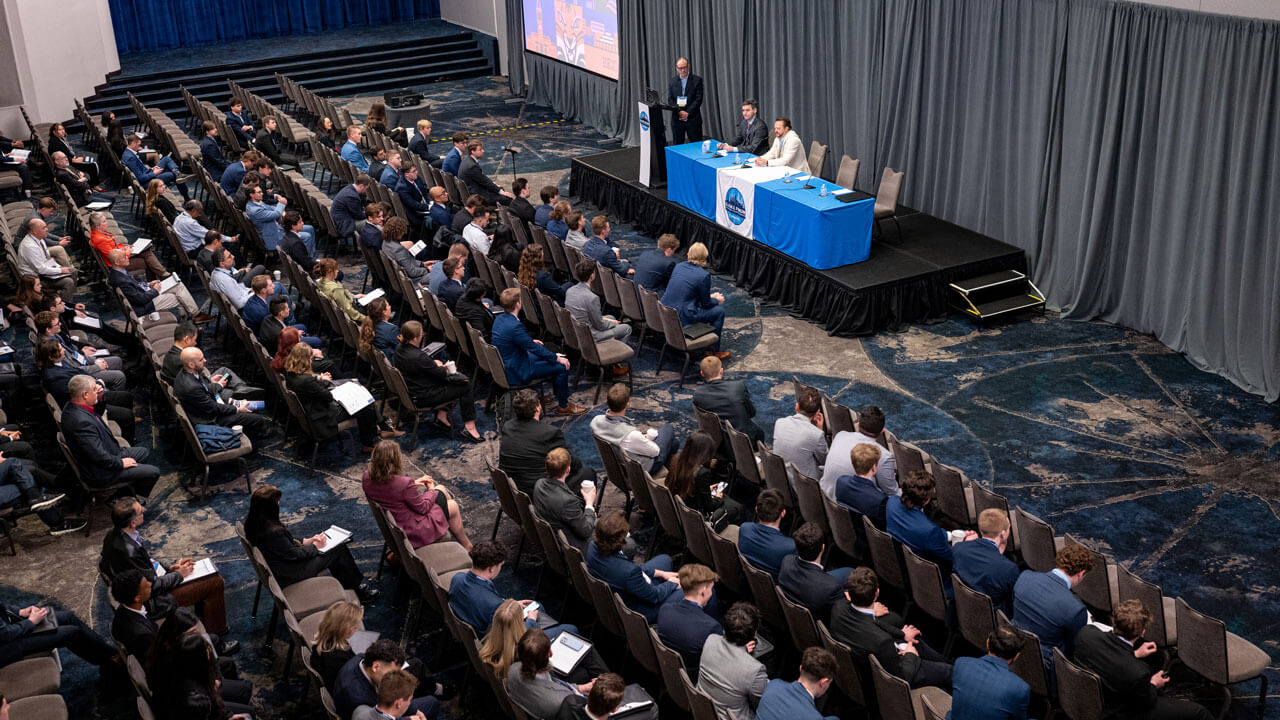 A room full of people listen to the panelists.