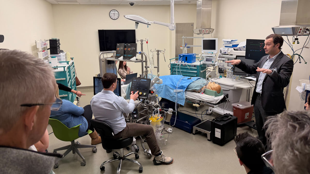 A male professor lecturing in a simulated operating room.